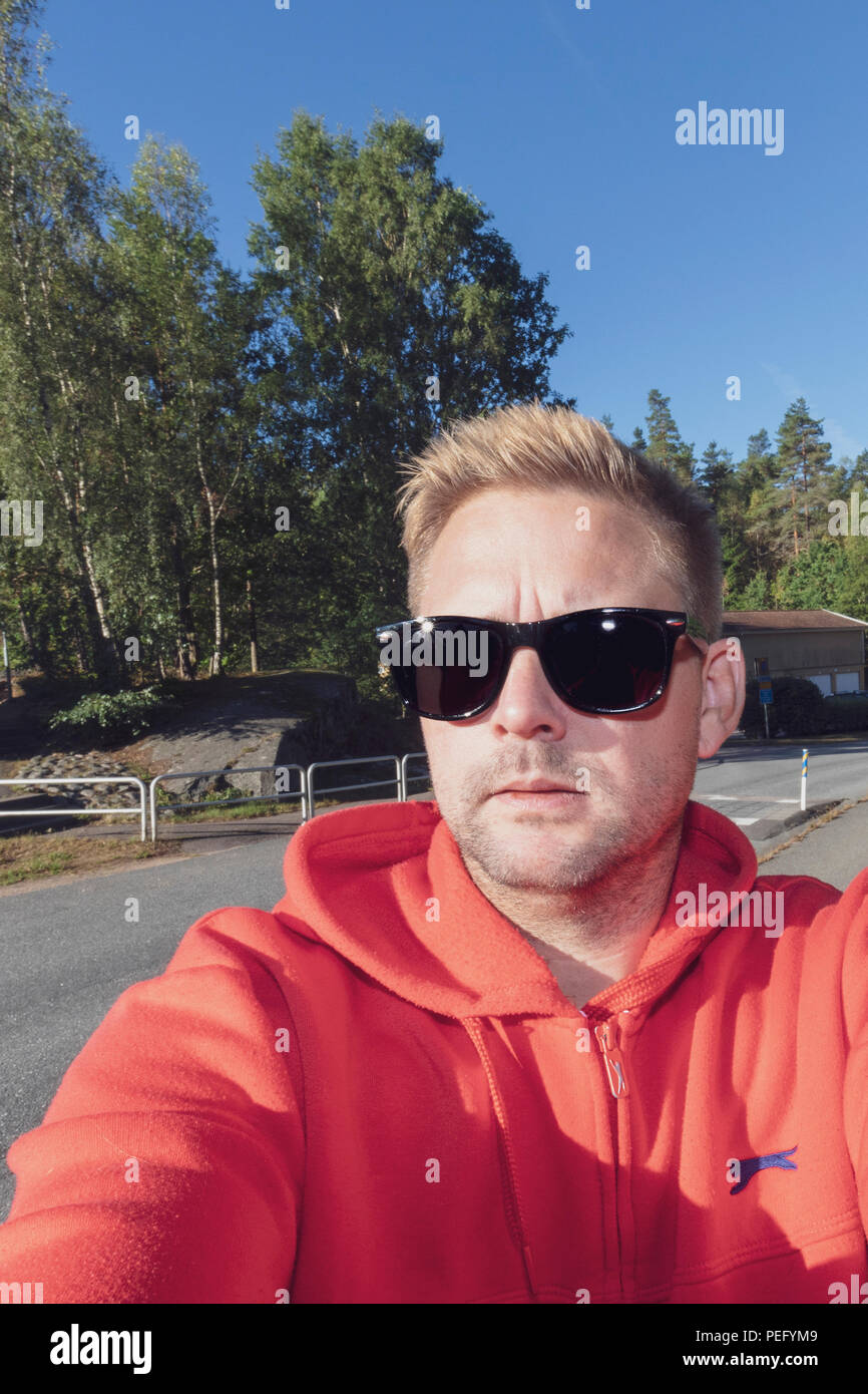 Metà uomo adulto in occhiali da sole prendendo un tipico stile selfie sulla strada Foto Stock