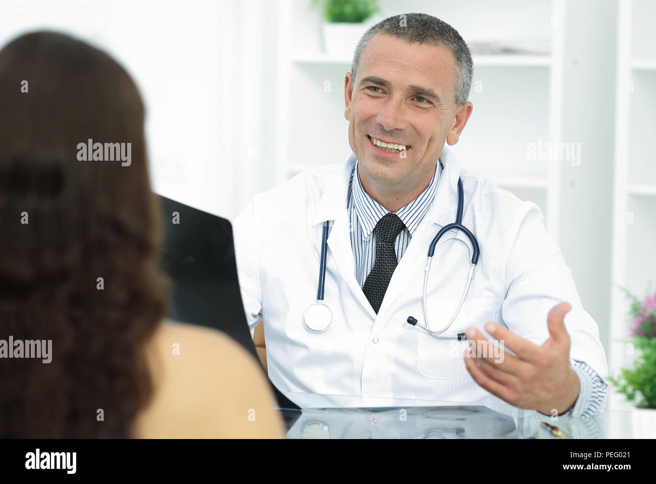 Medico a parlare con il paziente seduto a tavola Foto Stock