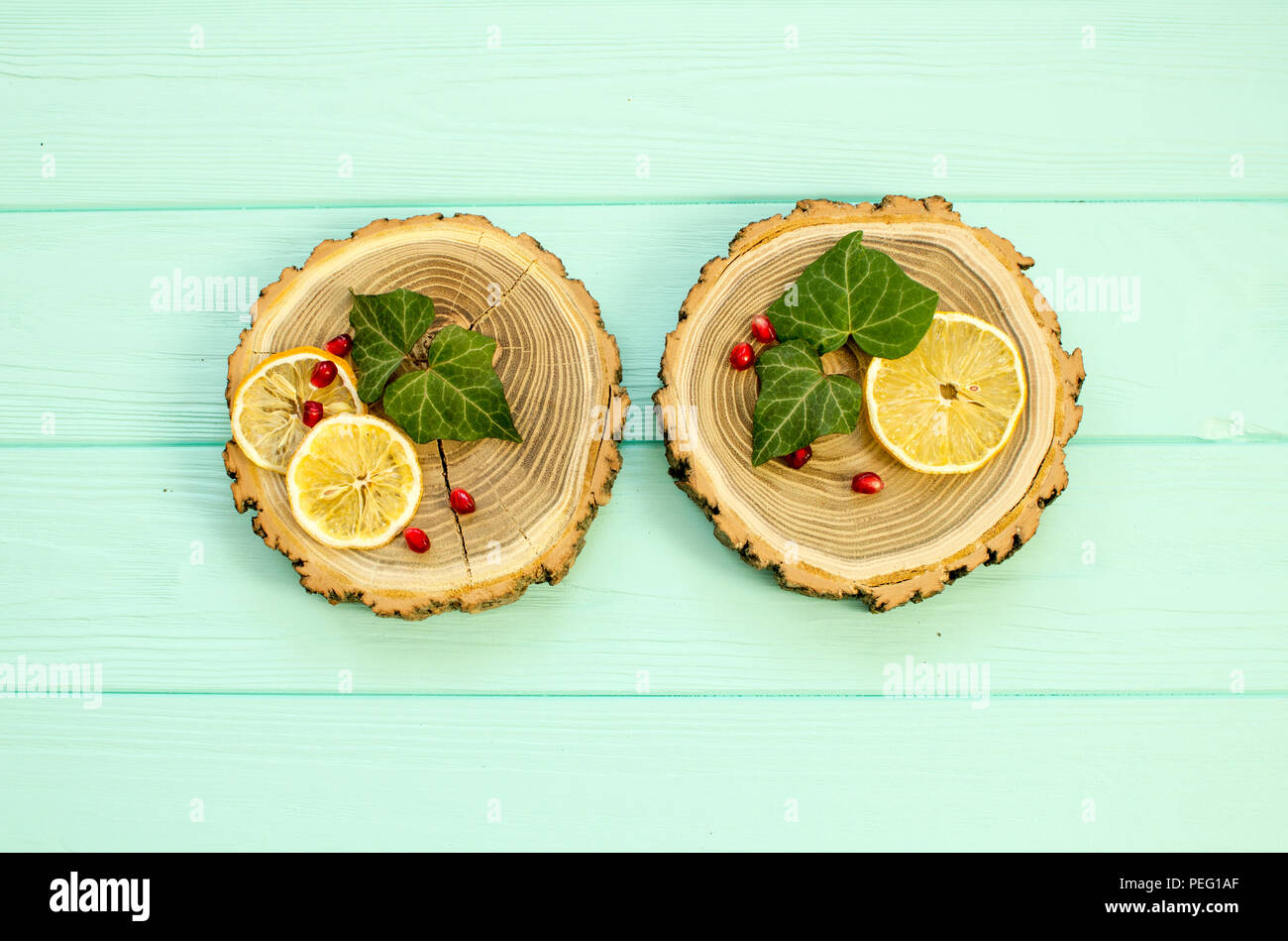 Taglio del legno con con fettine di limone e melograno bacche su un sfondo turchese Foto Stock
