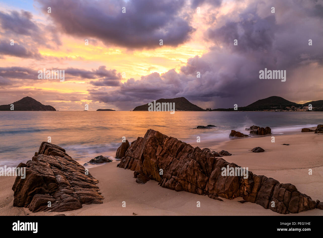 Nuvoloso Tramonto sull'oceano e la spiaggia rocciosa Foto Stock