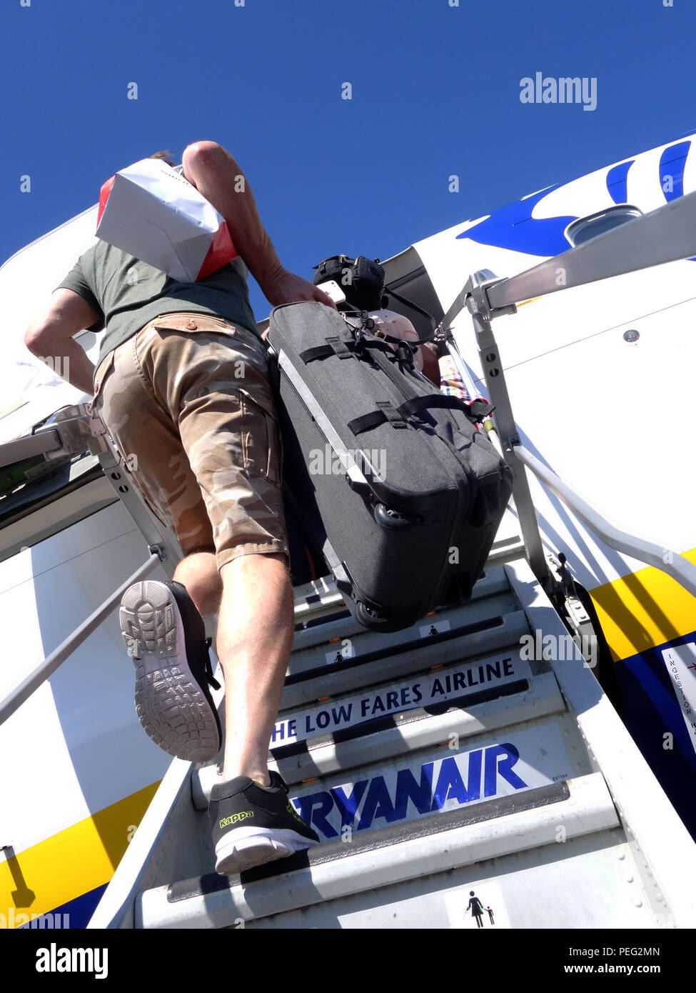 Vista posteriore del passeggero maschio si arrampica il piano passi a bordo di un volo Ryanair Foto Stock