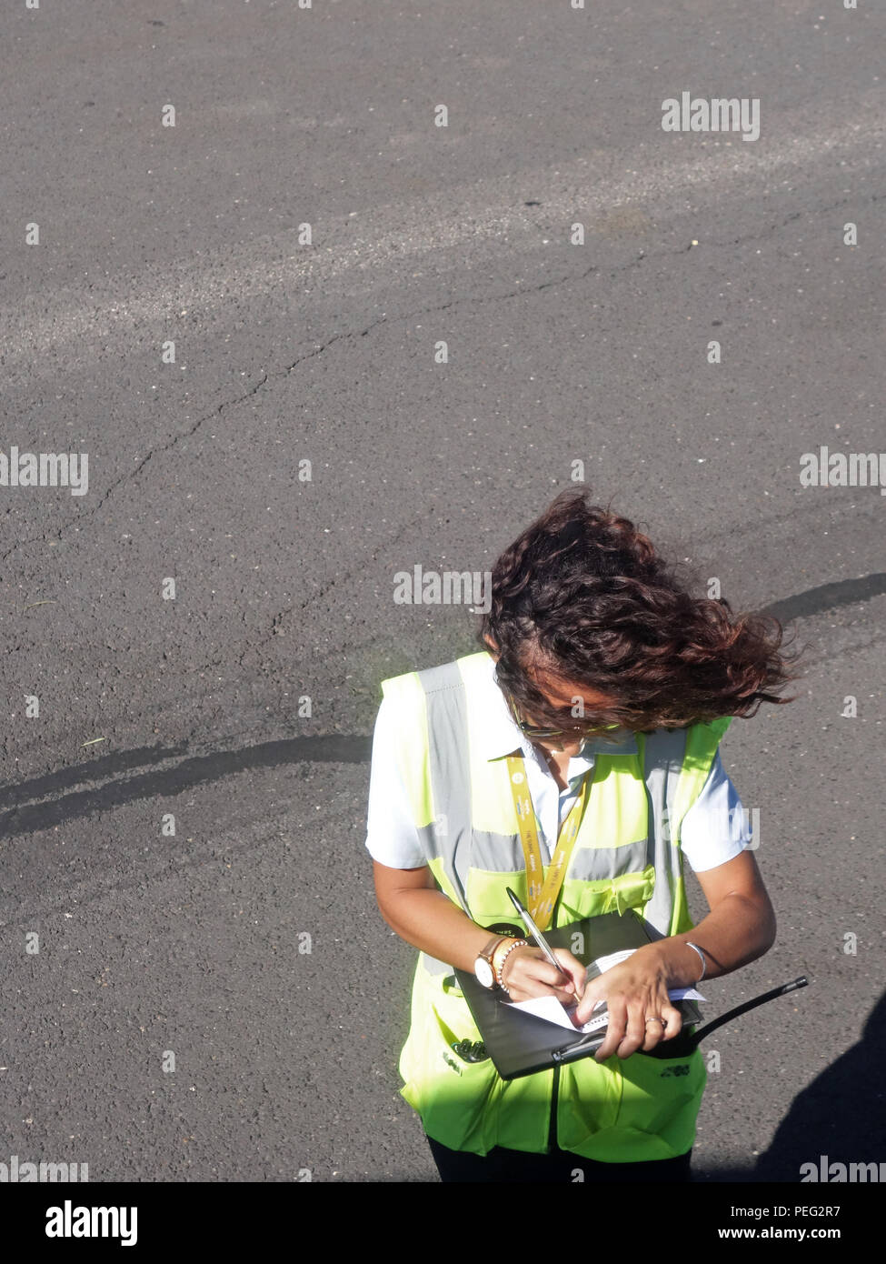 Signora spazzate dal vento il personale delle compagnie aeree piano di scrittura report di dettaglio mentre si sta in piedi sul piazzale aeroporto accanto ad un aereo Ryanair in aeroporto di Beziers Foto Stock