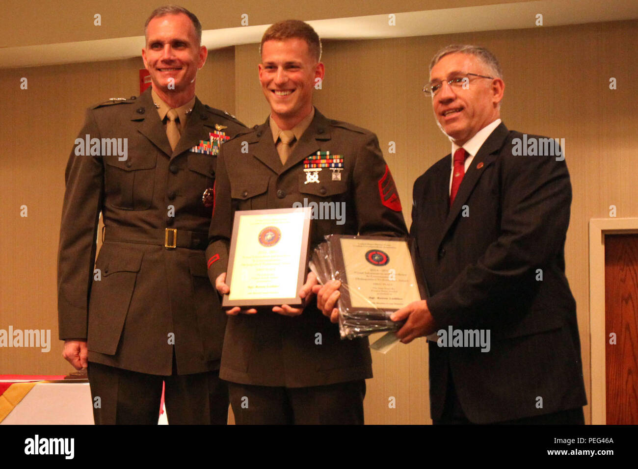 Il Mag. Gen. Gary Thomas, sinistra e Manny Pacheco, destro presente Sgt. Reece Lodder con diversi premi durante gli Stati Uniti Marine Corps combattere corrispondenti premi associazione banchetto presso l'Hilton Double Tree Hotel in New Bern, Carolina del Nord, 19 Agosto, 2015. Il USMCCCA ha ospitato il banchetto in onore di ospiti illustri e i vincitori nella lotta contro i corrispondenti comunità. Thomas è il comandante generale di 2 aeromobili marino ala. Lodder è una massa communications specialist con USMC Stazione di reclutamento di Seattle. Pacheco è il presidente della USMCCCA. Foto Stock