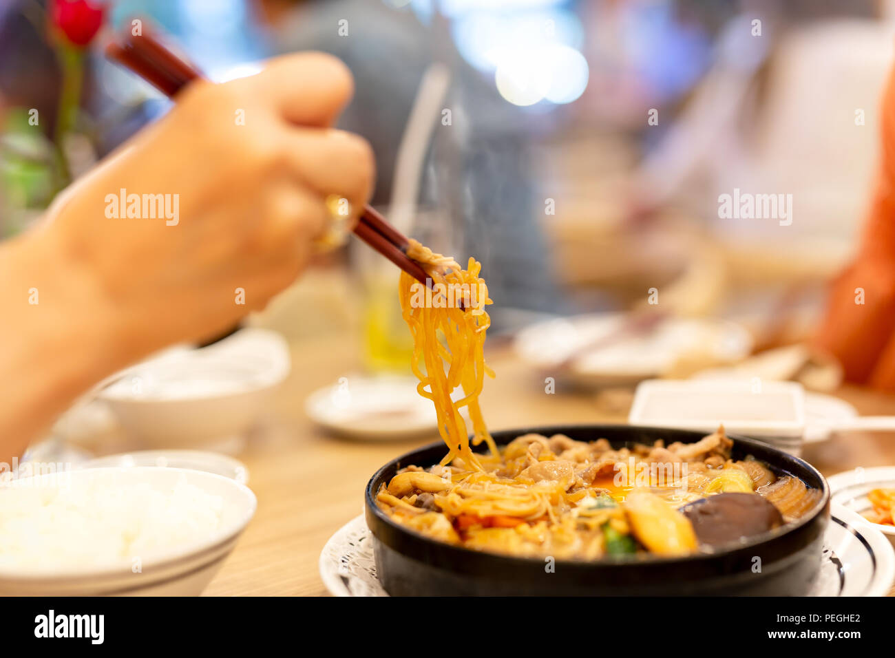Mano con bacchette di mangiare giapponese udon noodles. Foto Stock