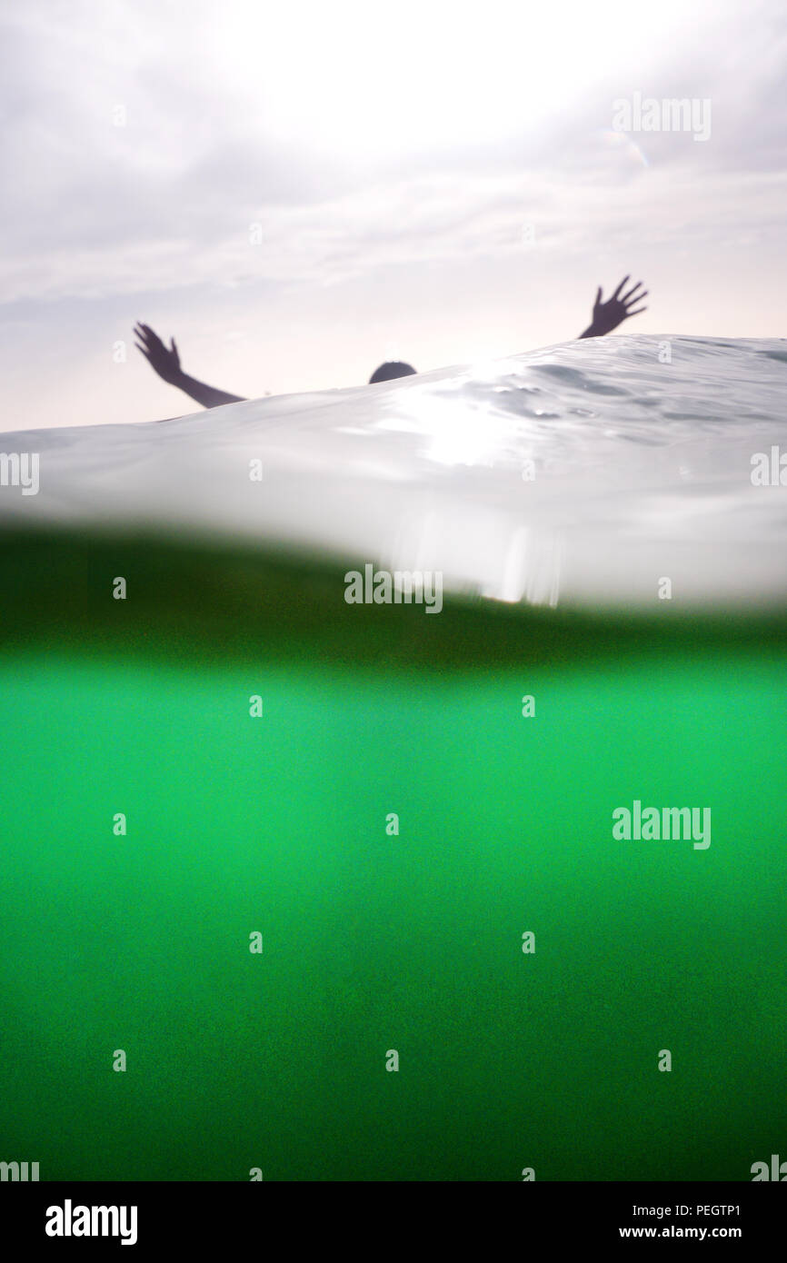 A cinquanta anni di donna di mani braccia e testa provenienti dal mare, la metà inferiore della fotografia è sotto il mare e il turchese, la metà superiore è Foto Stock