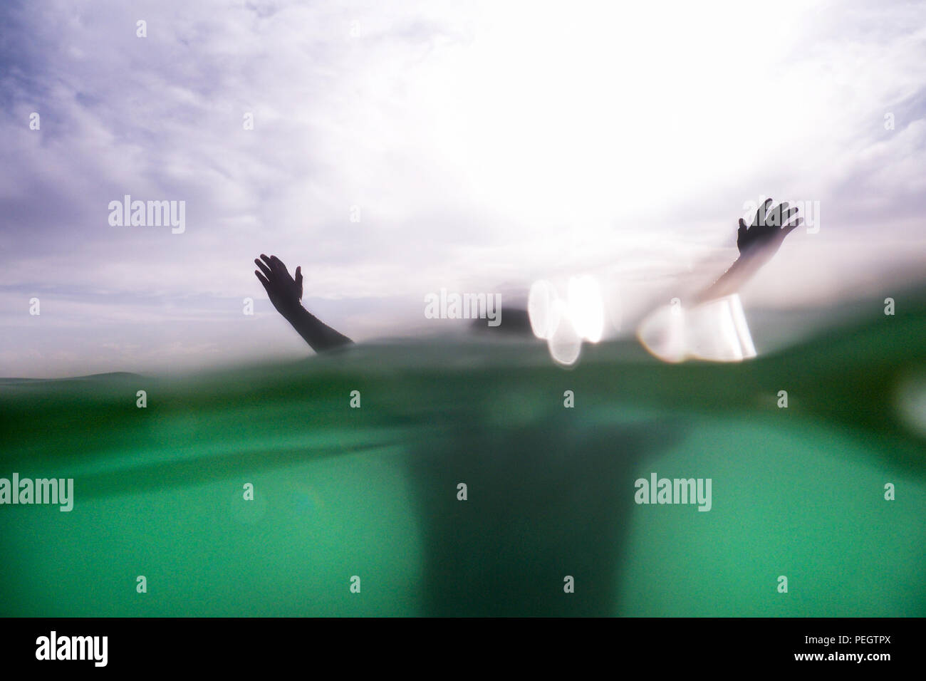 A cinquanta anni di donna di mani braccia e testa provenienti dal mare, la metà inferiore della fotografia è sotto il mare e il turchese, la metà superiore è Foto Stock