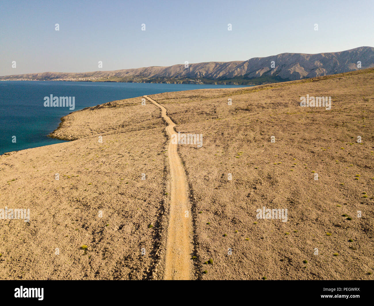 Vista aerea di una tortuosa strada che corre lungo le coste croate, sterrato, isola di Pag vicino Rucica beach a Metajna. Selvaggio e incontaminato Foto Stock