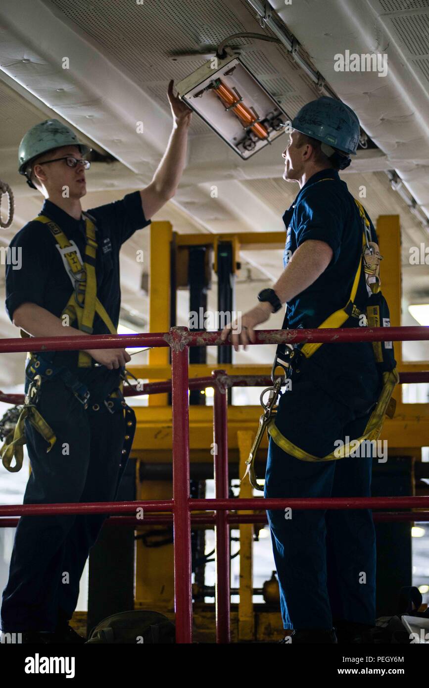 150824-N-DA-737-023 OCEANO PACIFICO (Agosto 24, 2015) - Da elettricista, Mate Fireman Richard Mueller, da Marysville, nello Stato di Washington, e da elettricista, Mate 2a classe Giordania Miller, dalla forcella di spagnolo, Utah, collegare un apparecchio luminoso in USS John C. Stennis' (CVN 74) hangar bay. I marinai da John C. Stennis Strike gruppo sono sottoposti a formazione composita dell'Unità Esercizio e Joint Task Force Esercizio (COMPTUEX/JTFEX), la fase finale nella certificazione di distribuire. (U.S. Foto di Marina di Massa lo specialista di comunicazione di terza classe Jonathan Jiang / rilasciato) Foto Stock
