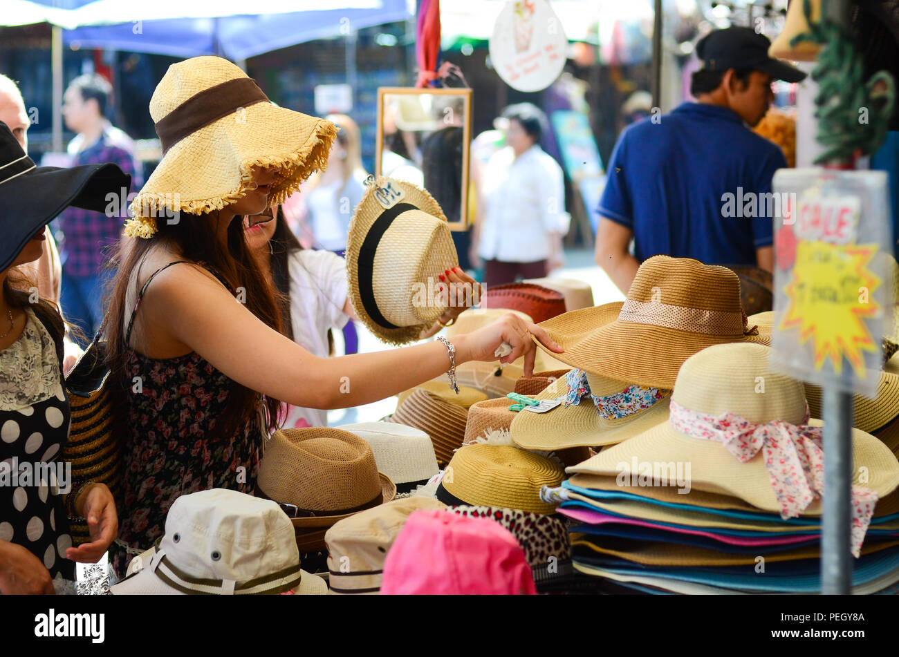 Una donna shopping per un cappello al mercato di Chatuchak a Bangkok, in Thailandia. Foto Stock