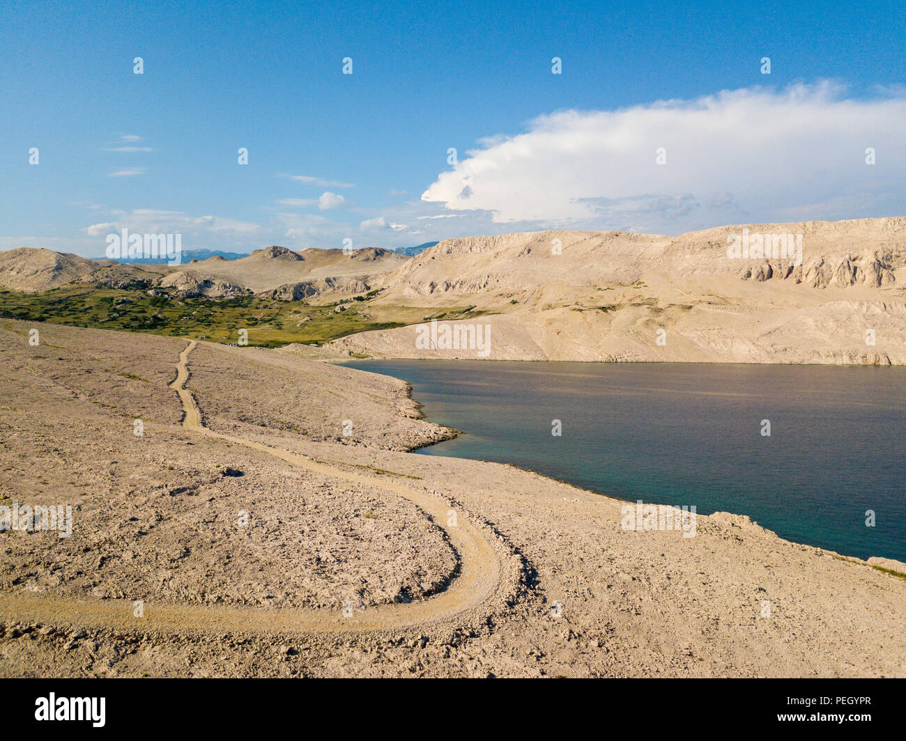 Vista aerea di una tortuosa strada che corre lungo le coste croate, sterrato, isola di Pag vicino Rucica beach a Metajna. Selvaggio e incontaminato Foto Stock