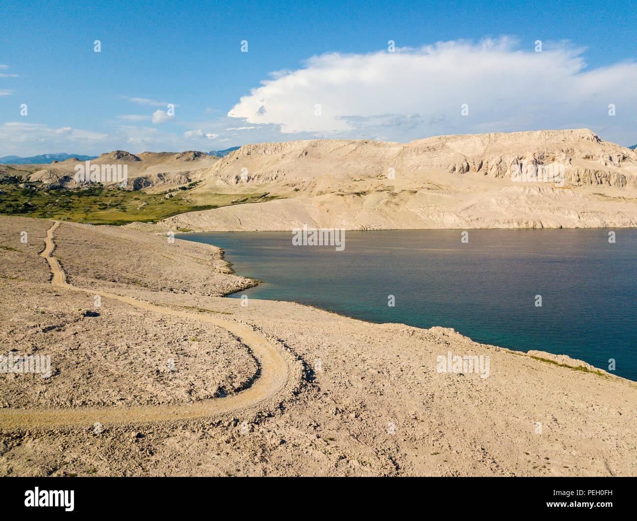 Vista aerea di una tortuosa strada che corre lungo le coste croate, sterrato, isola di Pag vicino Rucica beach a Metajna. Selvaggio e incontaminato Foto Stock