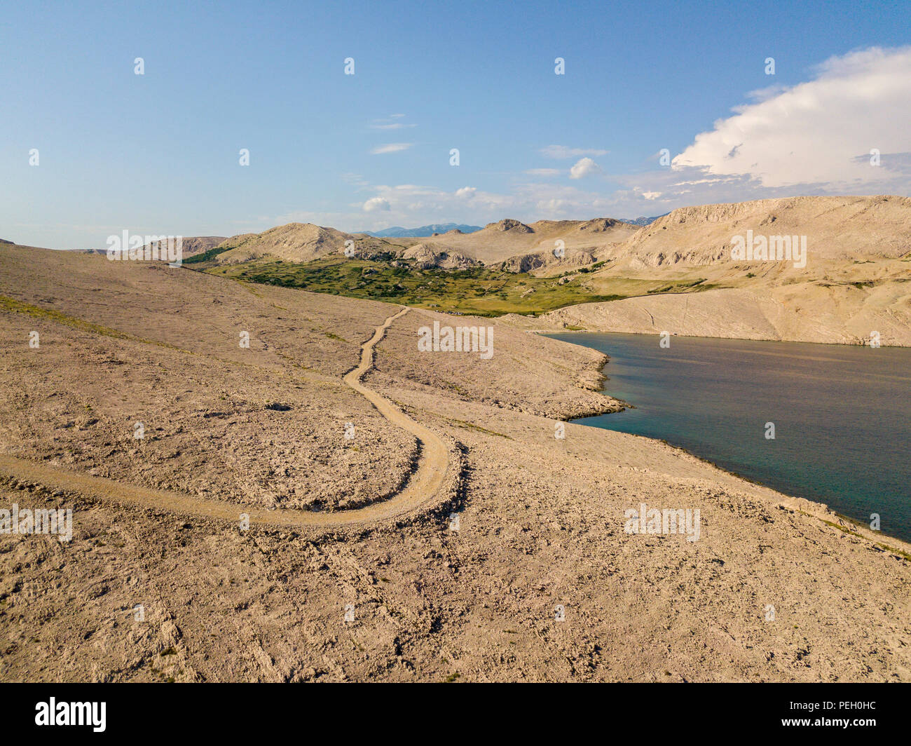 Vista aerea di una tortuosa strada che corre lungo le coste croate, sterrato, isola di Pag vicino Rucica beach a Metajna. Selvaggio e incontaminato Foto Stock