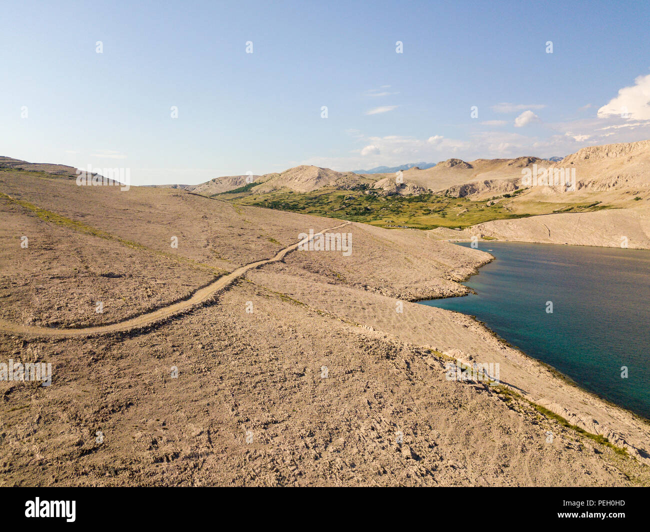 Vista aerea di una tortuosa strada che corre lungo le coste croate, sterrato, isola di Pag vicino Rucica beach a Metajna. Selvaggio e incontaminato Foto Stock