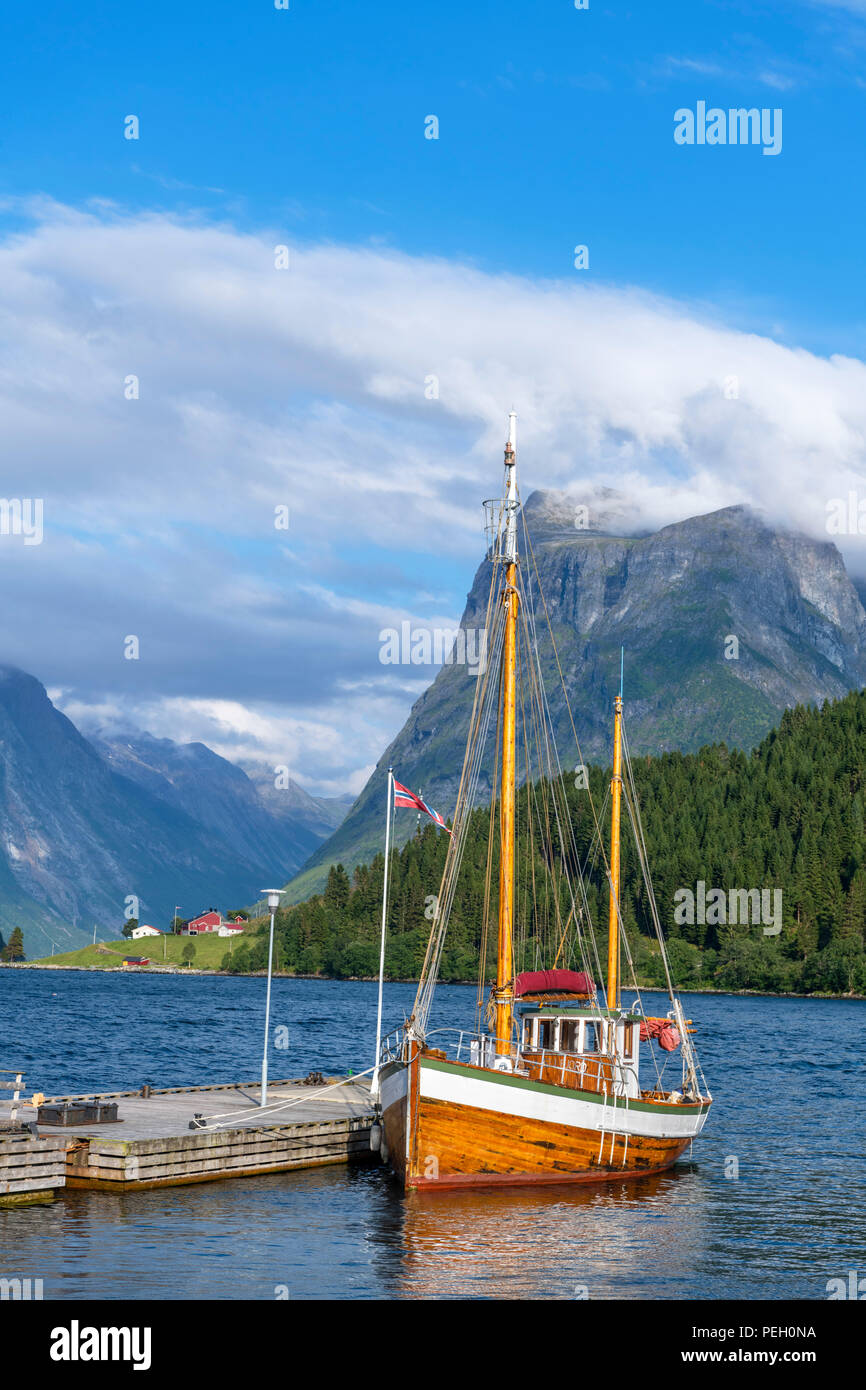 Fiordi Norvegesi. Tradizionale imbarcazione attraccata ad un molo al di fuori il Sagafjord hotel nel tardo pomeriggio, Saebø, Hjørundfjorden, Møre og Romsdal, Norvegia Foto Stock