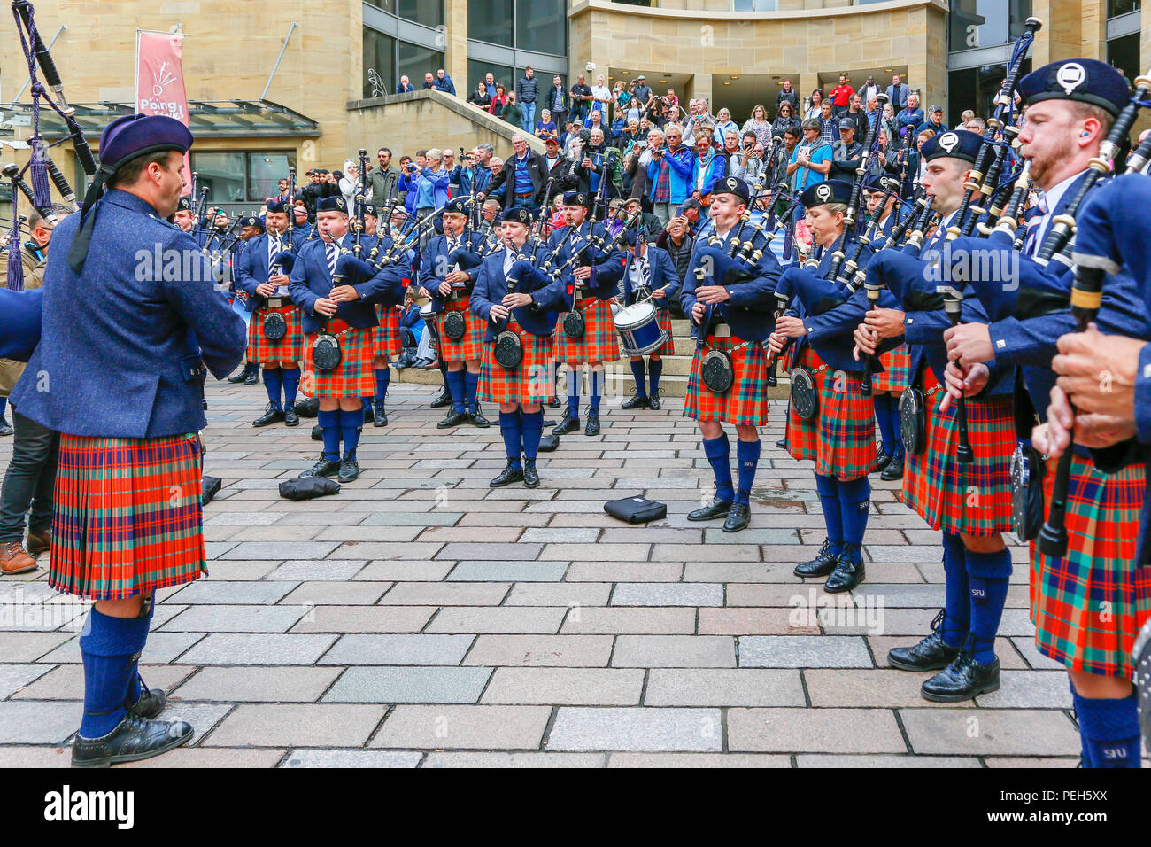 Glasgow, Regno Unito. 15 agosto 2018. Le esibizioni di strada proseguono in Buchanan Street, Glasgow, con altre pipedband internazionali che suonano vicino alla statua di Donald Dewar per intrattenere il pubblico gratuitamente. I campionati Pipe Band si concludono sabato 18 agosto a Glasgow Green. Membri della Simon Fraser University Pipe Band della British Columbia, Canada Credit: Findlay/Alamy Live News Foto Stock