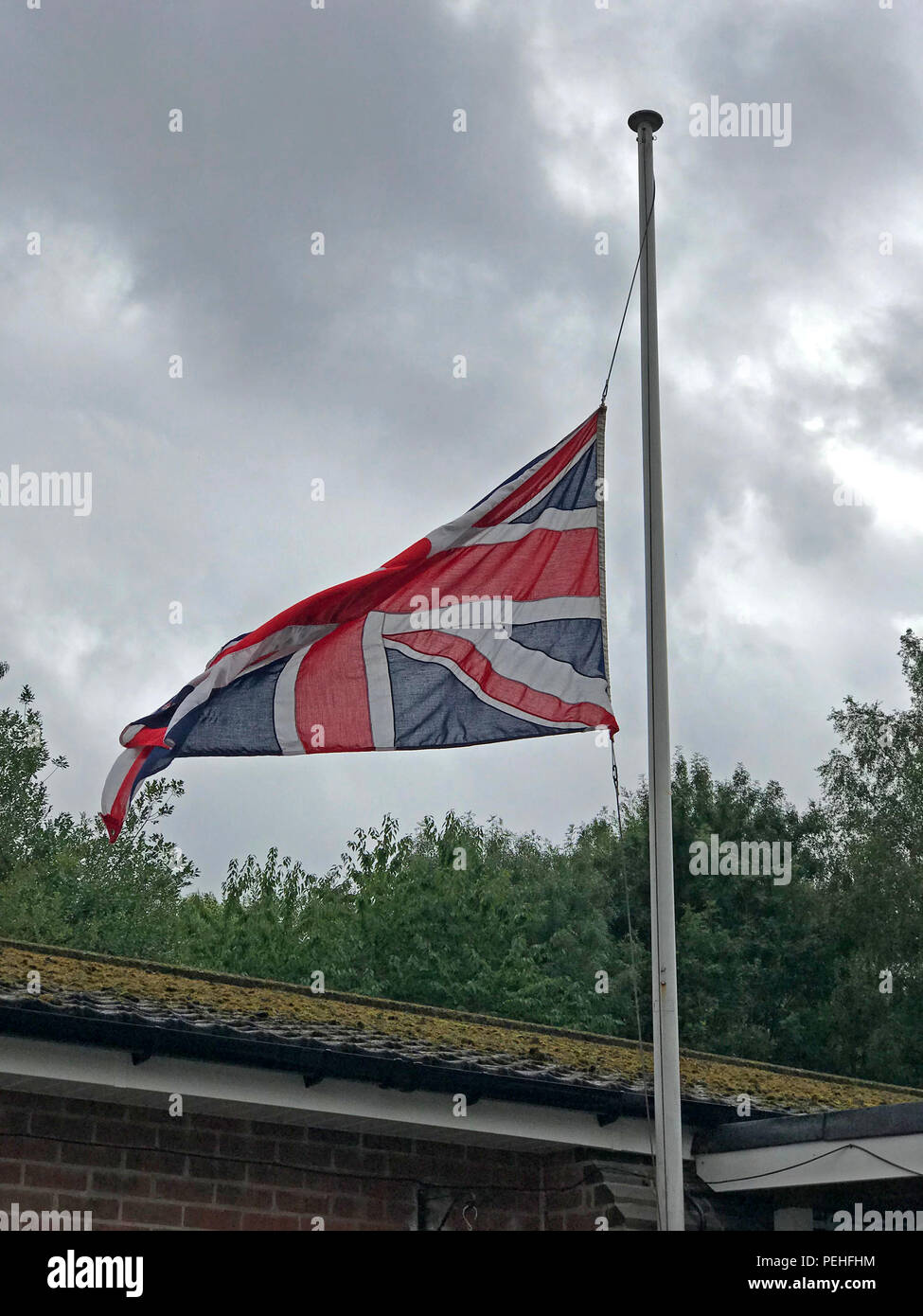 Bandiera europea, Unione Jack a mezz asta denota una morte, a Grappenhall & Thelwall British Legion, Warrington, Cheshire, North West England, Regno Unito Foto Stock