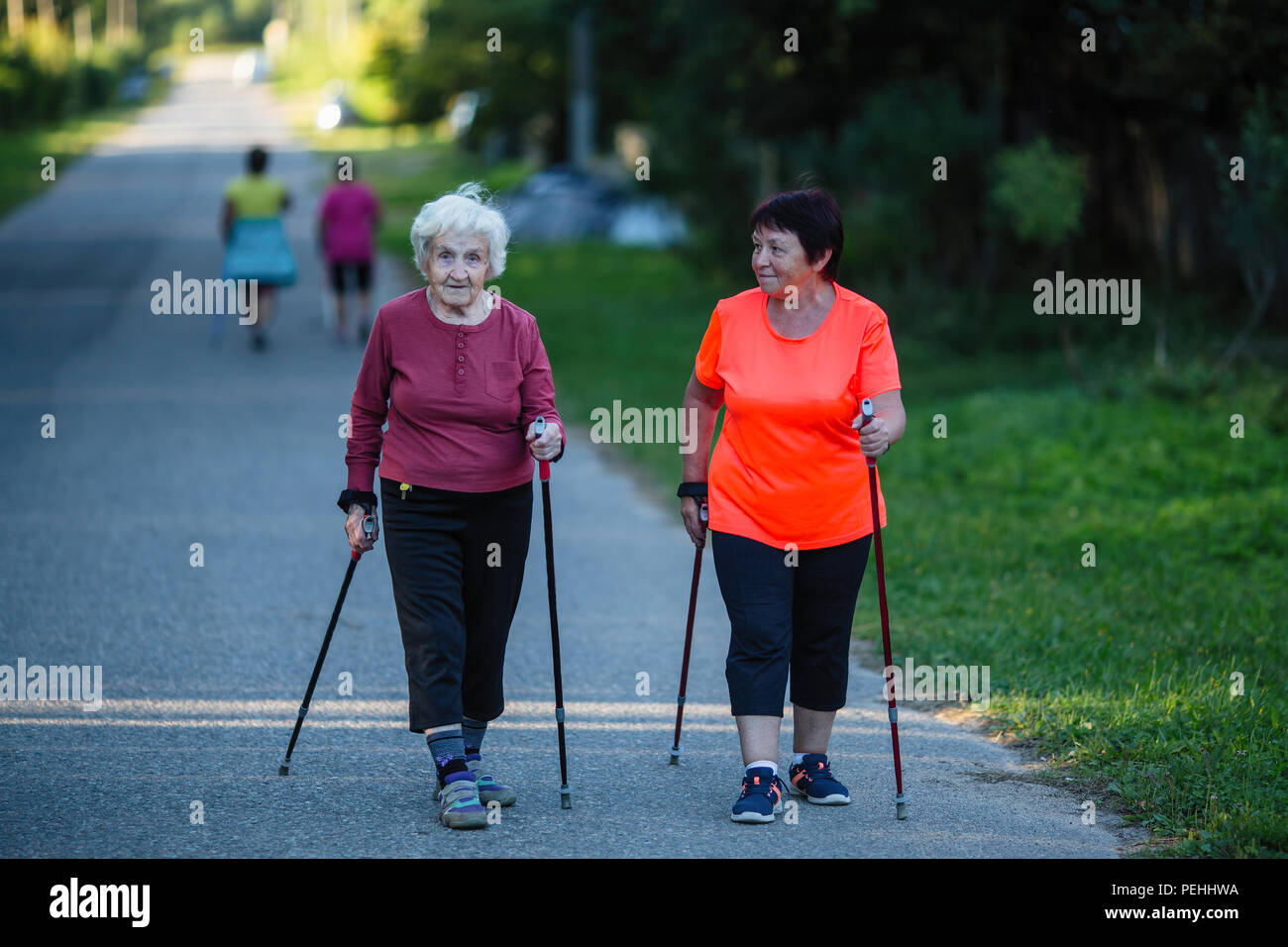 Una donna anziana è impegnato nel Nordic walking con sua figlia adulta. Foto Stock