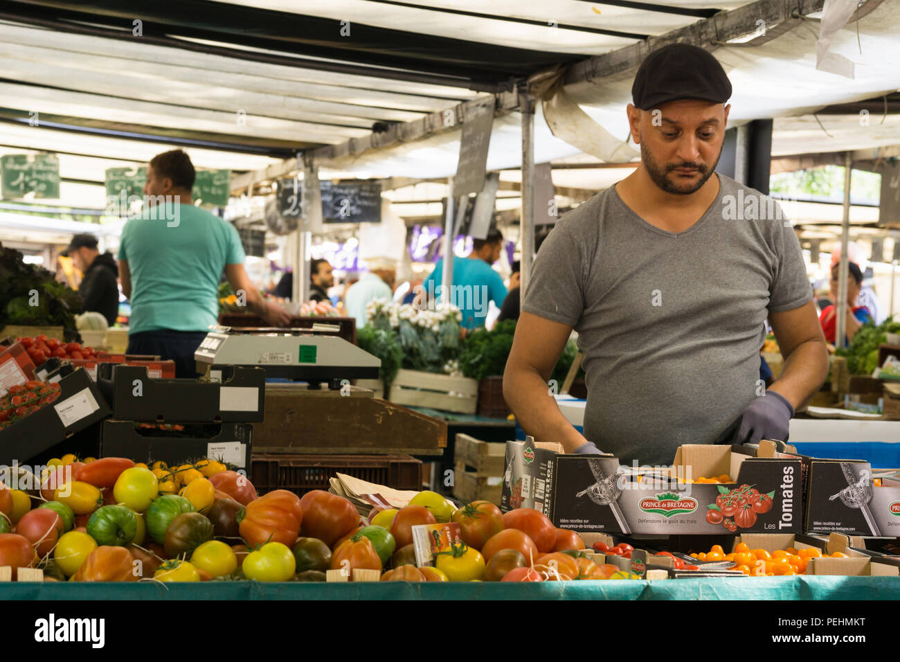 L'uomo vendere i pomodori a La Bastiglia mercato di fattoria a Parigi, Francia. Foto Stock