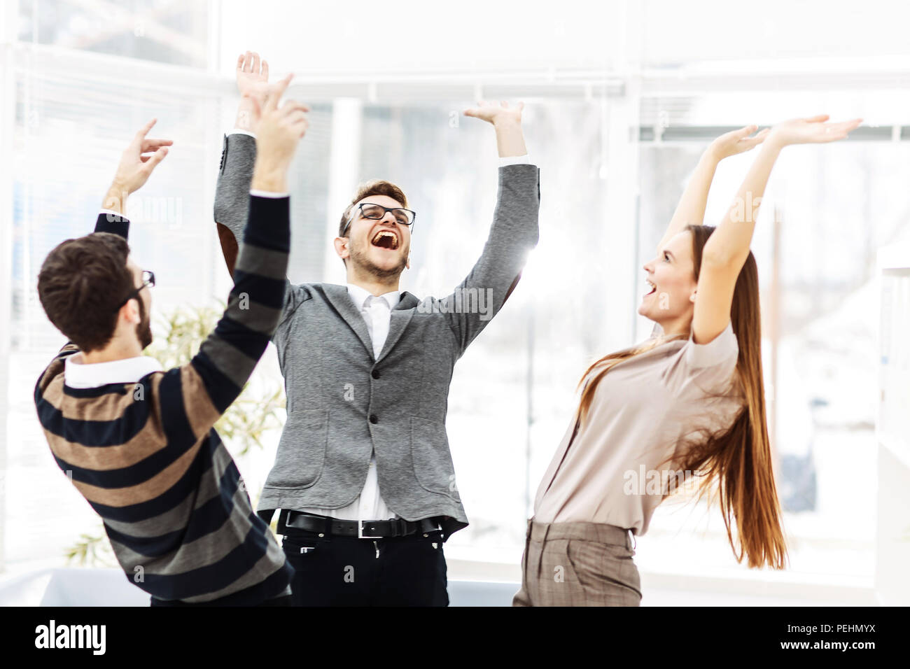 Concetto di vittoria - il giubilante team business in piedi in cerchio e con le mani fino a gioire il successo. Foto Stock