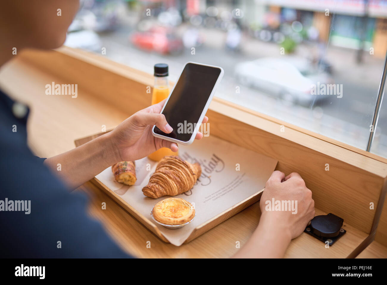 Ricerche maschio le informazioni necessarie sul sito internet tramite smart phone mentre si siede al Terrace cafe con succo di frutta e dessert Foto Stock