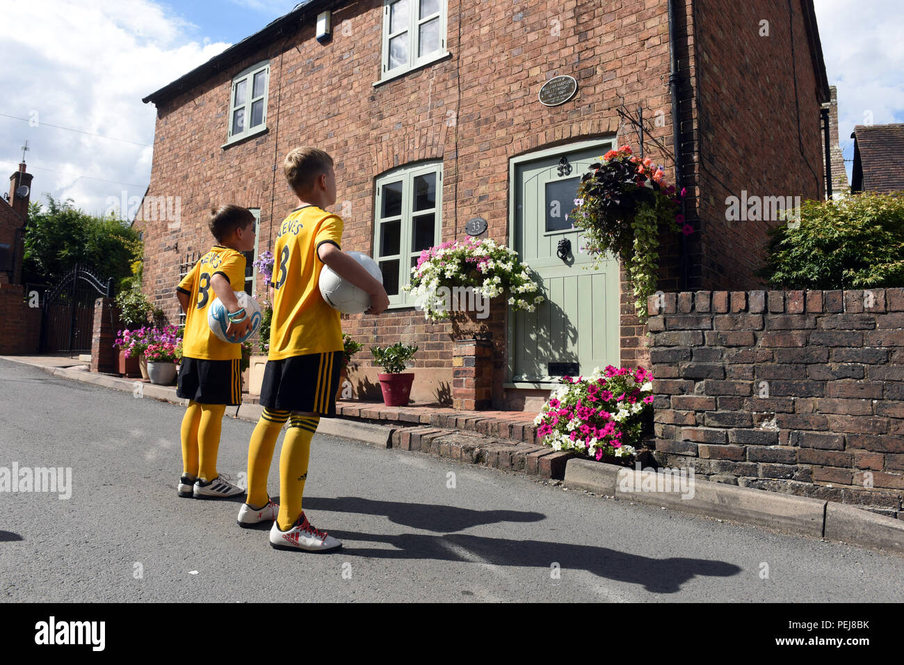 I ragazzi in Wolverhampton Wanderers FC kit replica a giocare a calcio al di fuori del luogo di nascita di lupi e Inghilterra leggenda calcistica di Billy Wright in Ironb Foto Stock