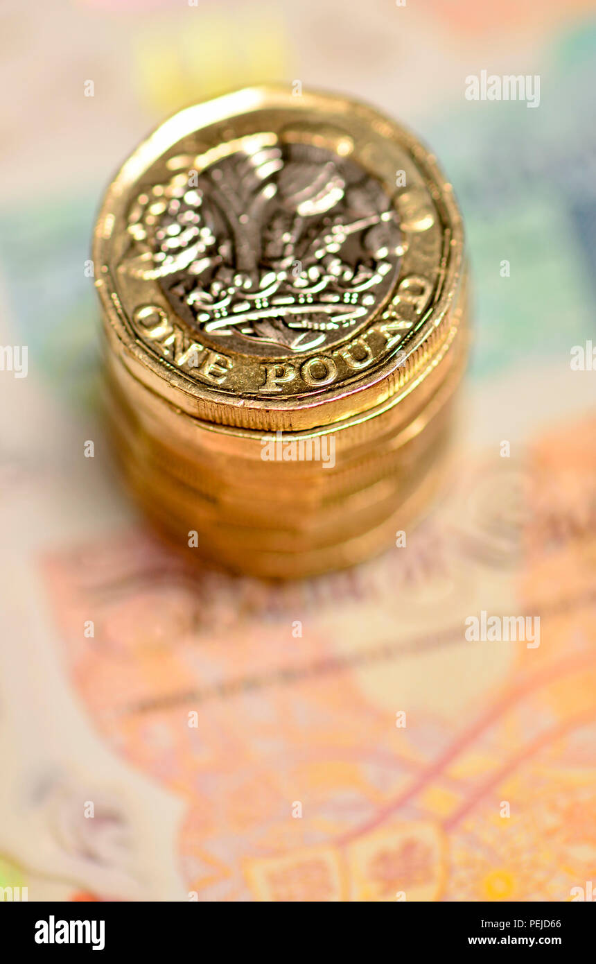 Pila di libbra di monete su British banconote Foto Stock
