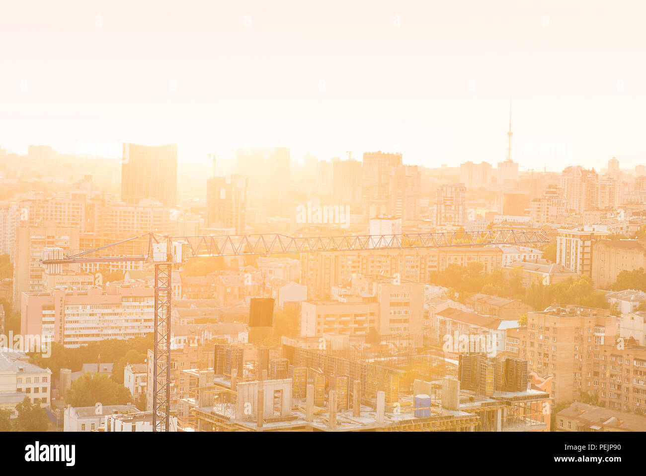 Gru da cantiere ed edifici in costruzione nella città urbana scape in indietro la luce del tramonto. Residenziale o aziendale per lo sviluppo delle infrastrutture e e Foto Stock