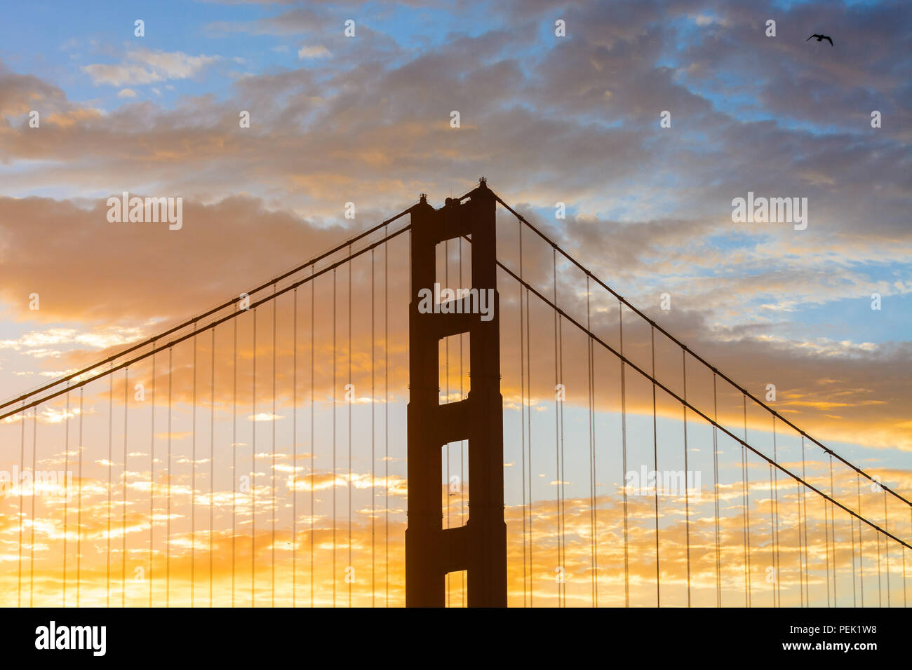 Un tramonto colorato comincia ad emergere dietro una delle torri del Golden Gate Bridge di San Francisco, CA. Foto Stock