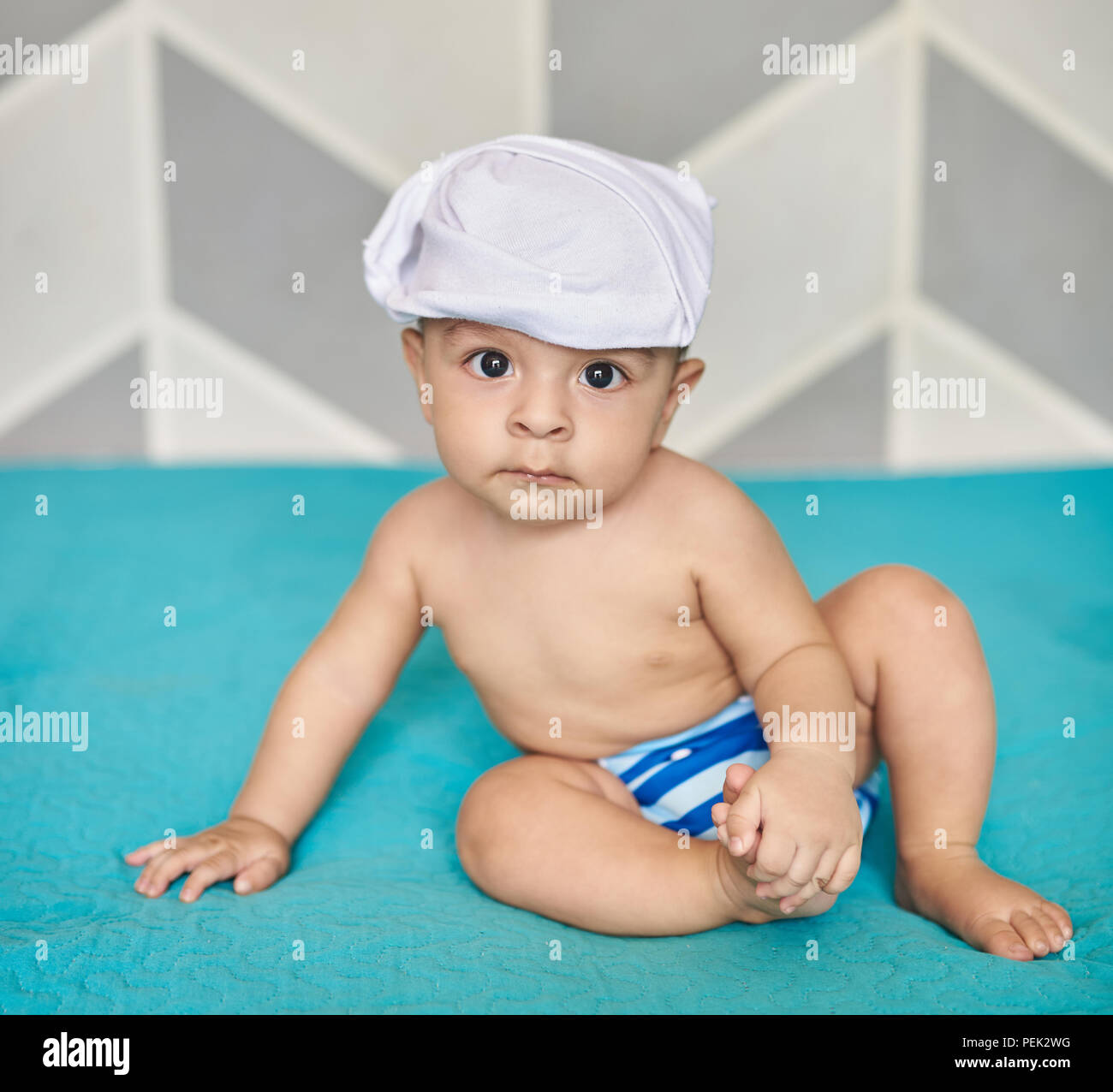 Baby boy in stoffa pannolino sedersi sul letto soffice coltre Foto Stock