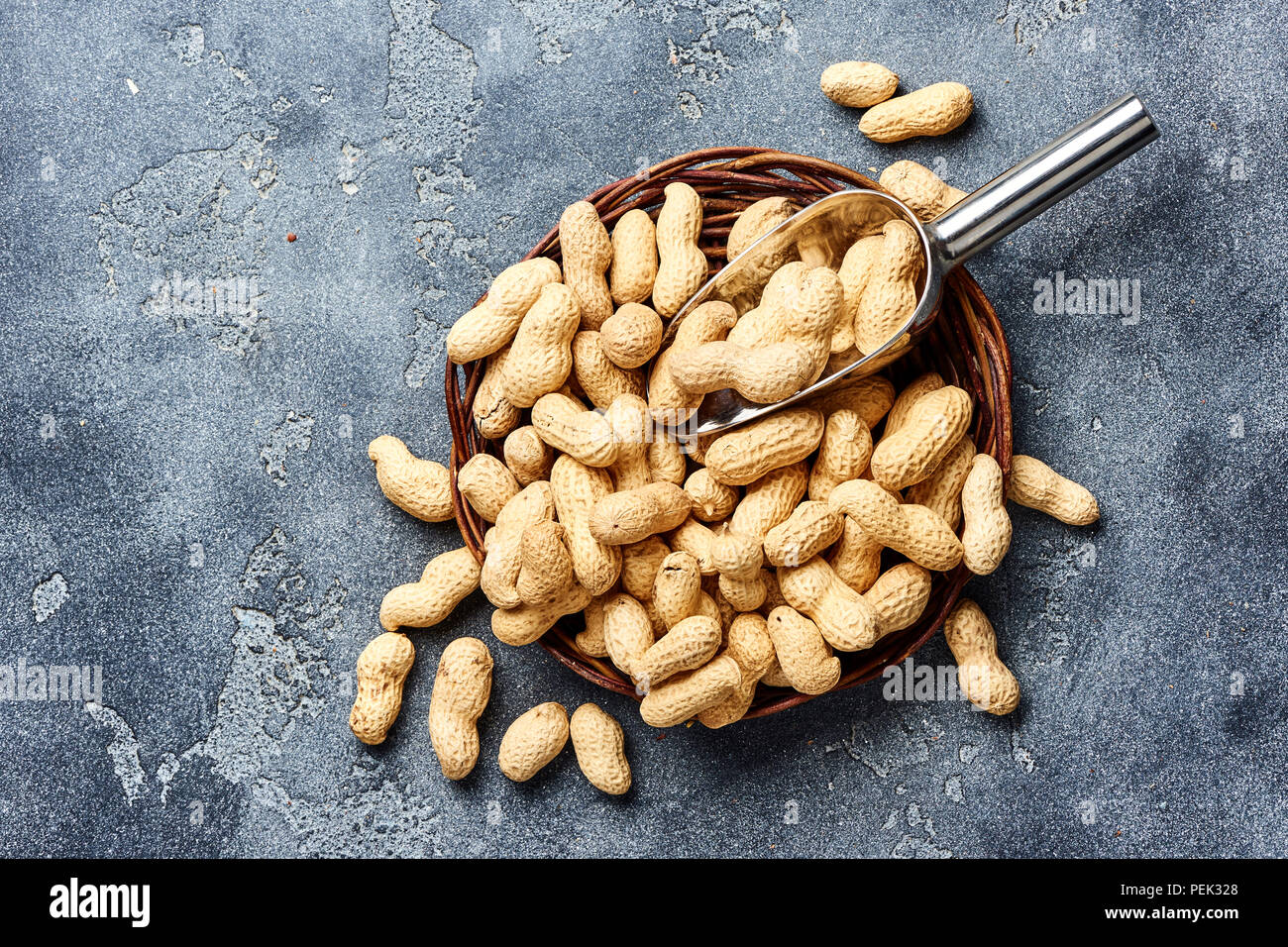 Arachidi in guscio di noce con scoop su sfondo grigio. Vista dall'alto di dadi. Foto Stock