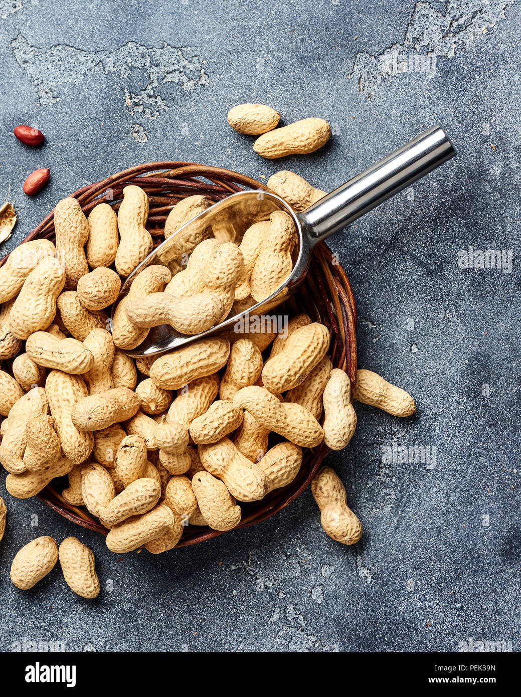 Arachidi in guscio di noce con scoop su sfondo grigio. Vista dall'alto di dadi. Foto Stock