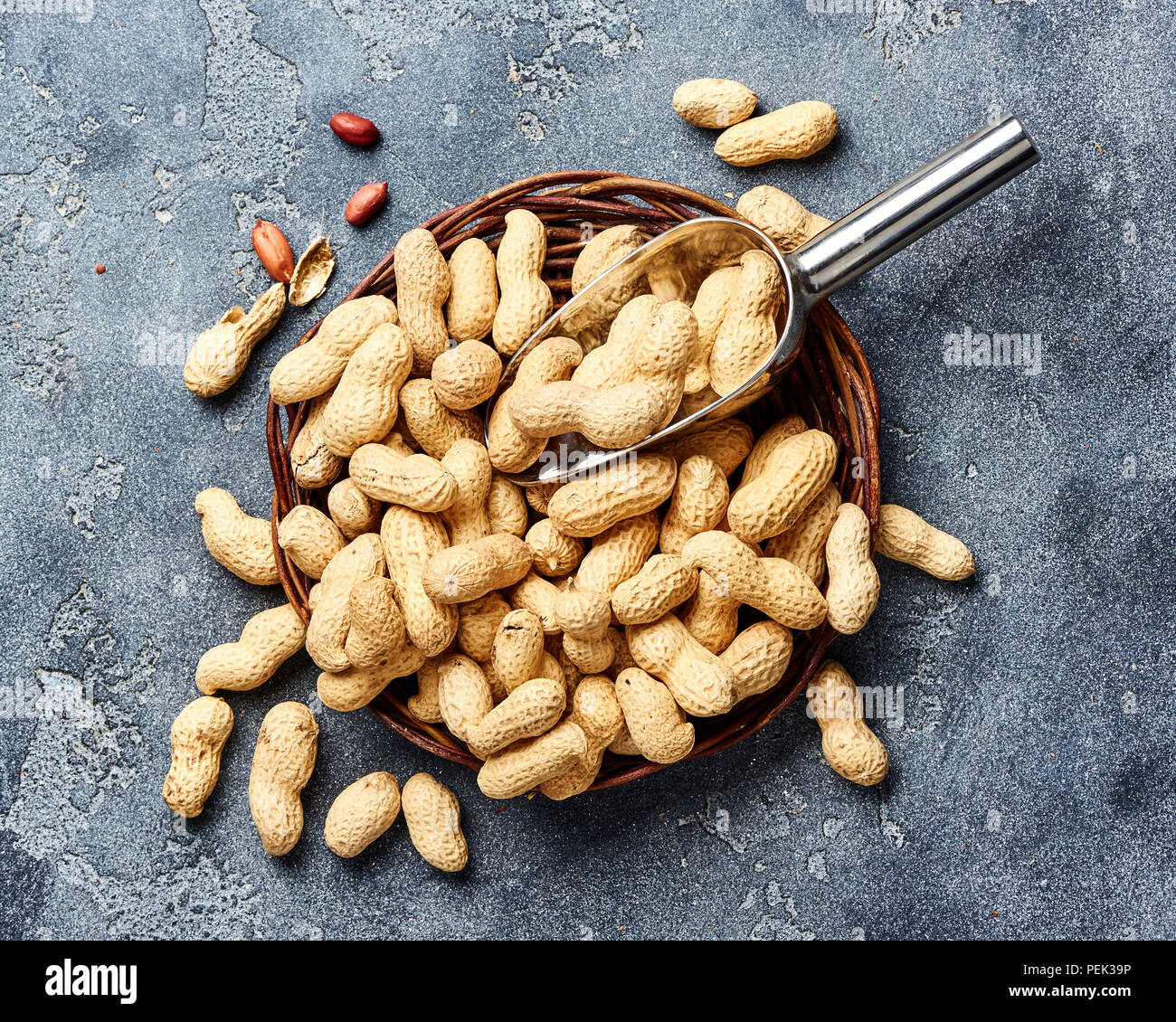 Arachidi in guscio di noce con scoop su sfondo grigio. Vista dall'alto di dadi. Foto Stock
