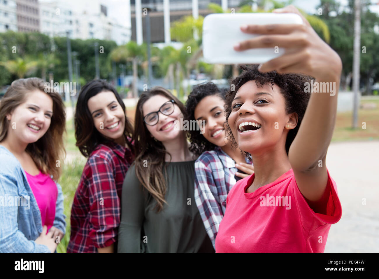 African American donna prendendo selfie con gruppo di amiche internazionale all'aperto in estate in città Foto Stock