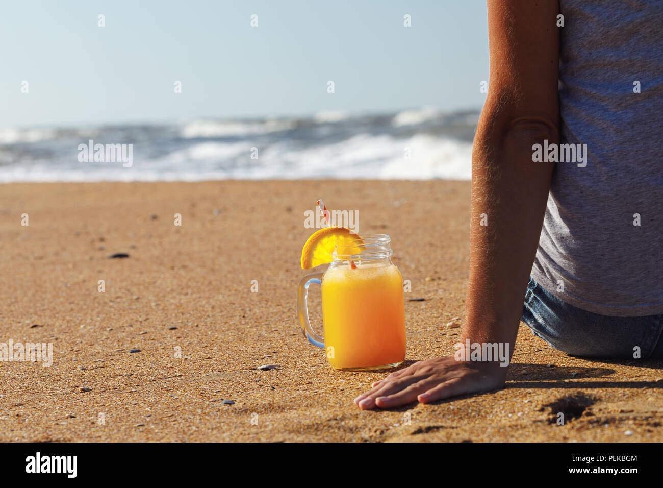 Succo di arancia con polpa in un barattolo sulla spiaggia vicino a riposo turistico, spazio per il testo Foto Stock