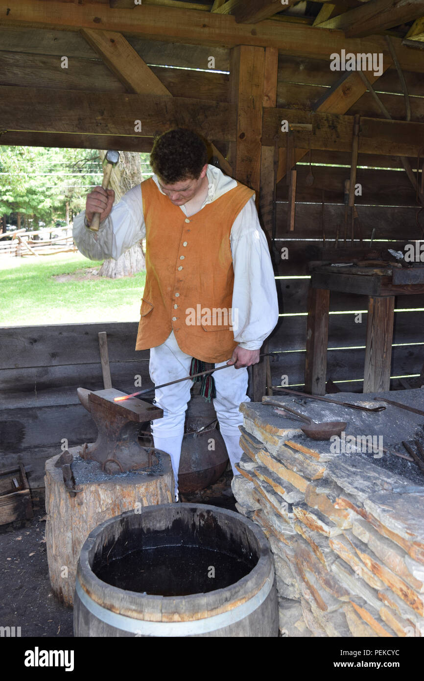 Una dimostrazione di un fabbro ferraio coloniale la lavorazione del ferro. Foto Stock