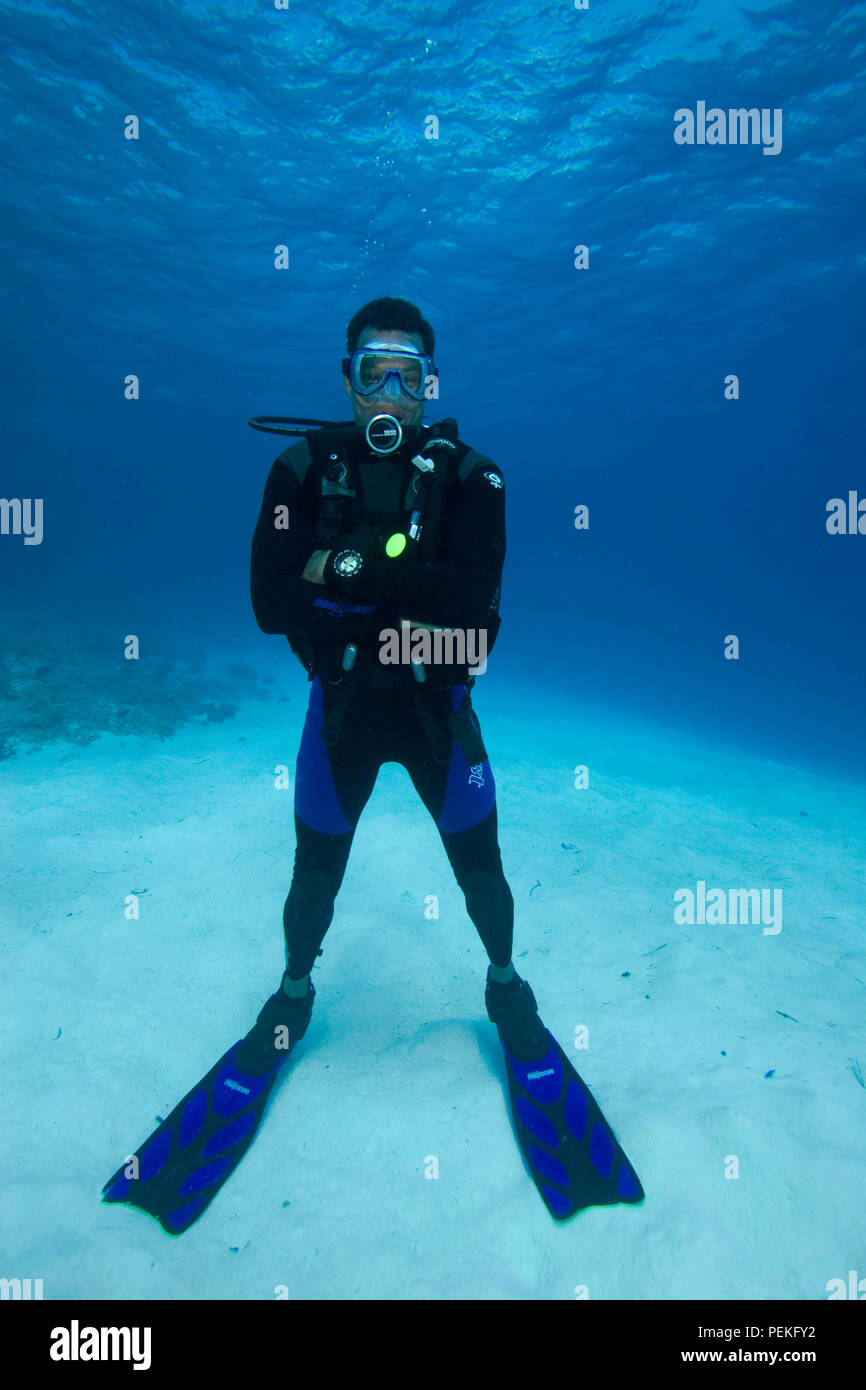 Un maschio diver (MR), con le braccia incrociate, in piedi su un fondo di sabbia, Palau Micronesia. Foto Stock