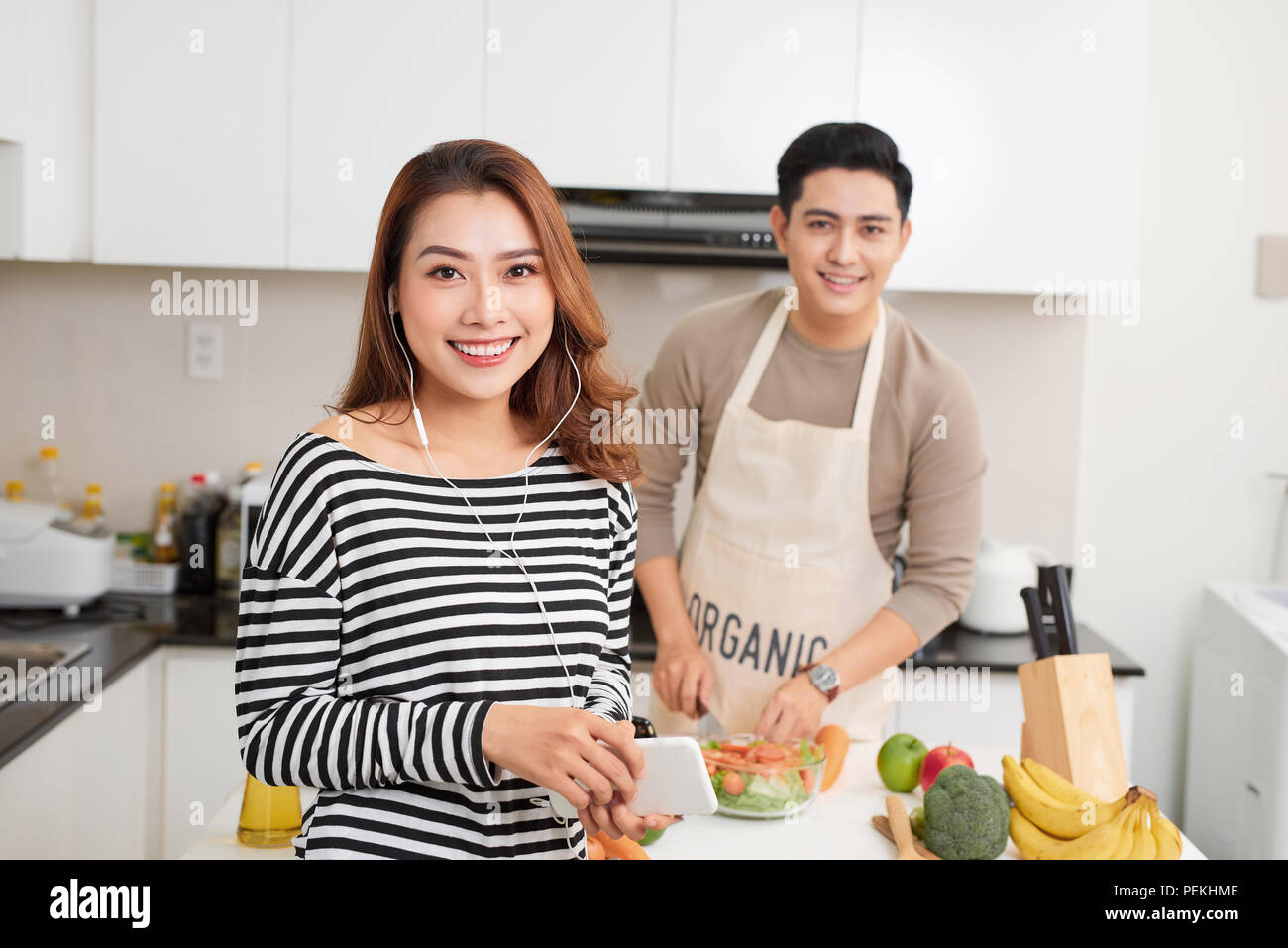 Bella coppia Giovane è la cottura nella cucina di casa.Man è la cottura con Moman è utilizzando una tavoletta digitale e sorridente. Foto Stock