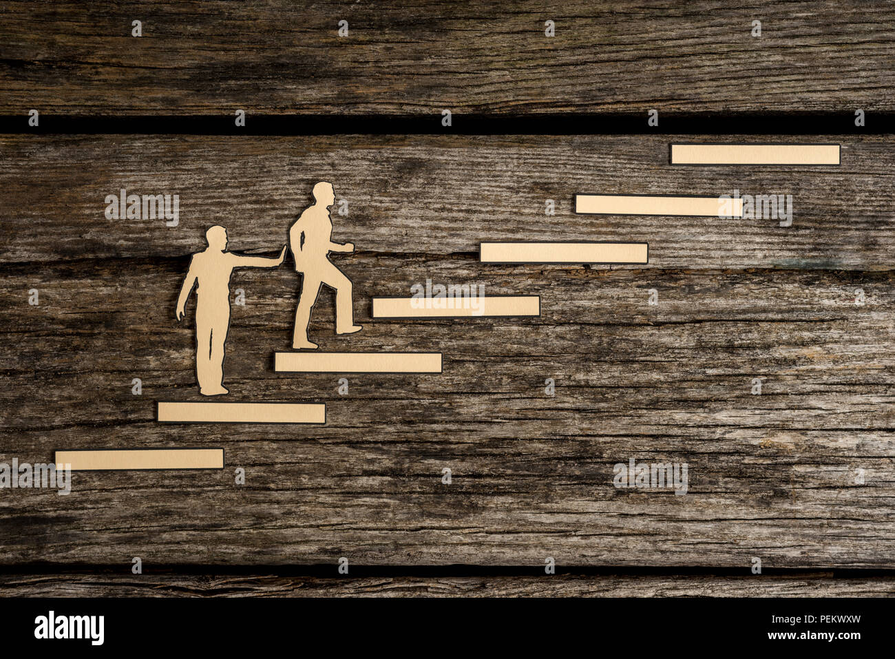 Ritagli di carta uomini con uno per aiutare spingere da dietro e l'altra salire le scale su legno rustico. Concettuale del partenariato. Foto Stock