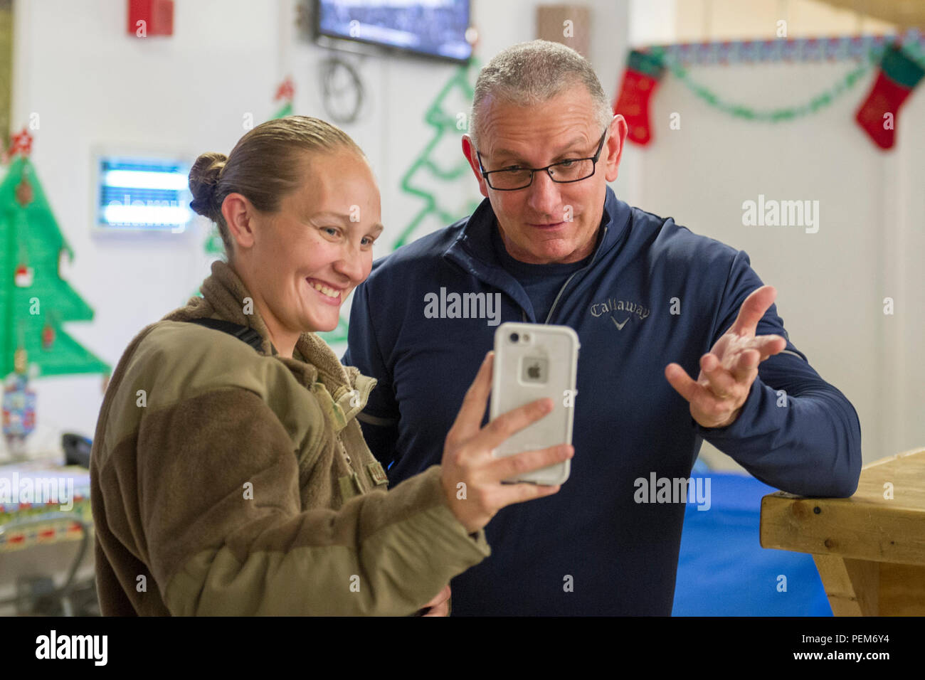 Celebrity Chef Robert Irvine fa un video personalizzato con il personale. Sgt. Jeanette Martinez, 455th Expeditionary Manutenzione aeromobili squadrone armi capo del team, durante un incontro e saluto con organi di servizio a Bagram Air Field, Afghanistan, Dic 17, 2015. Lo Chef Irvine ha concluso il suo Robert Irvine Live tour con l'OSU dopo la visita di numerose strutture a BAF. (U.S. Air Force foto di Tech. Sgt. Robert Cloys) Foto Stock