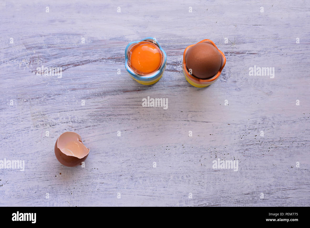Due uova sode o servito in tazza di uova alla luce sullo sfondo di legno/ sana colazione/ buona mattina Foto Stock