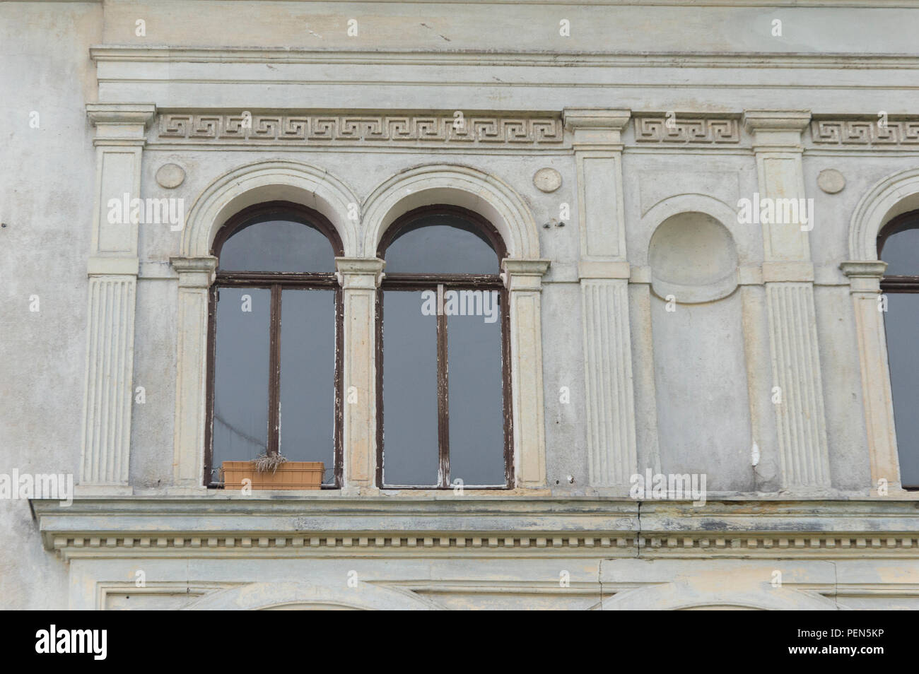 Nische mit Fenstern und Blumenkasten in verschmutzter Fassade Foto Stock