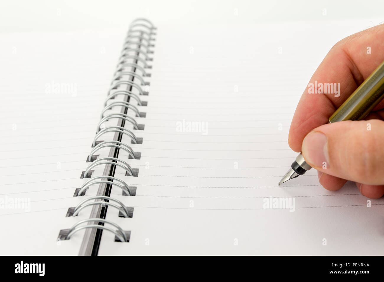 L'uomo la scrittura in un fustellato rilegato a spirale notebook con pagine rigate utilizzando una penna stilografica con copyspace per il tuo testo. Foto Stock