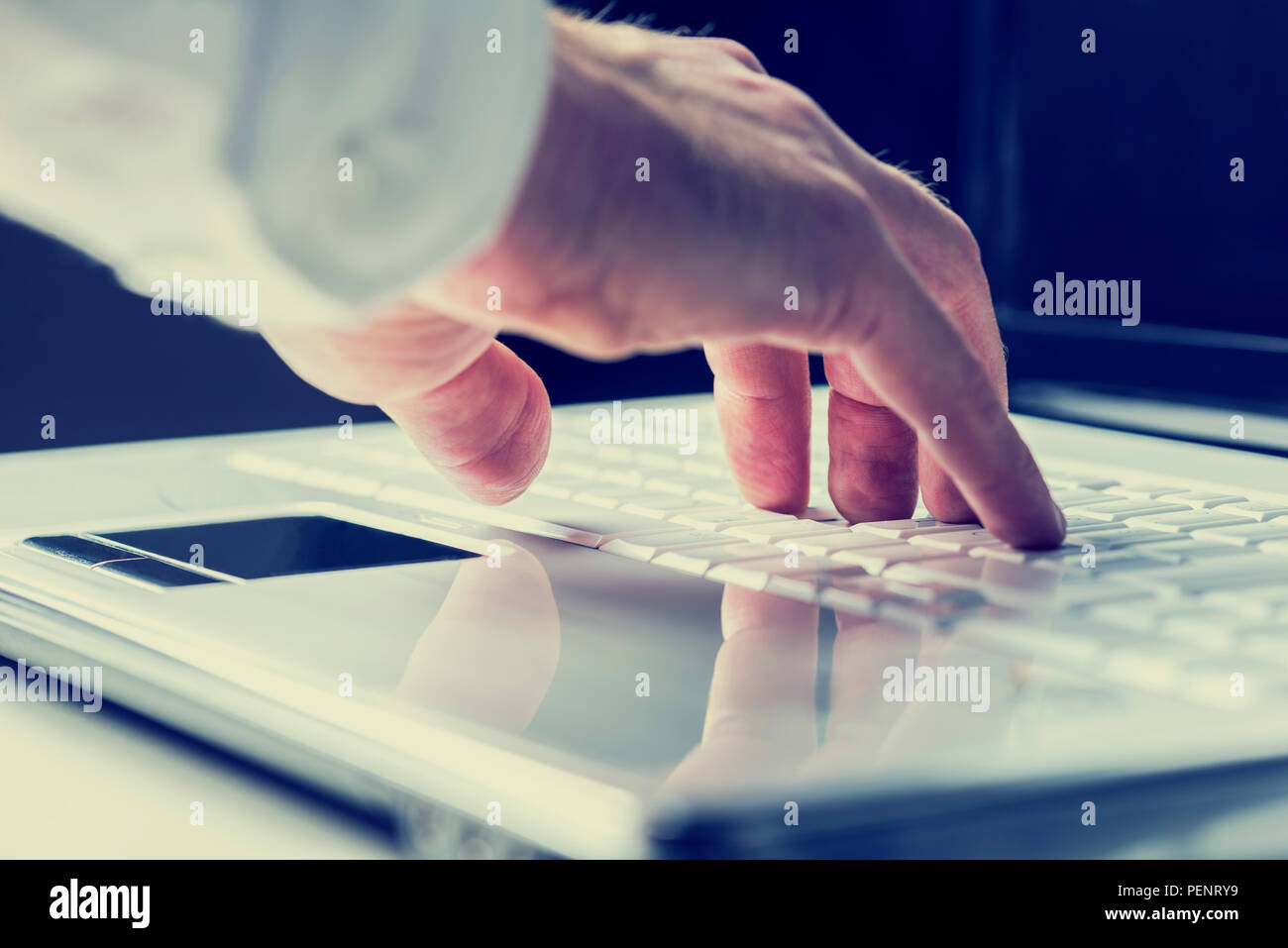 Primo piano delle mani di un uomo digitando su una tastiera portatile come egli immette informazioni o naviga su Internet in una comunicazione online e contattare concep Foto Stock