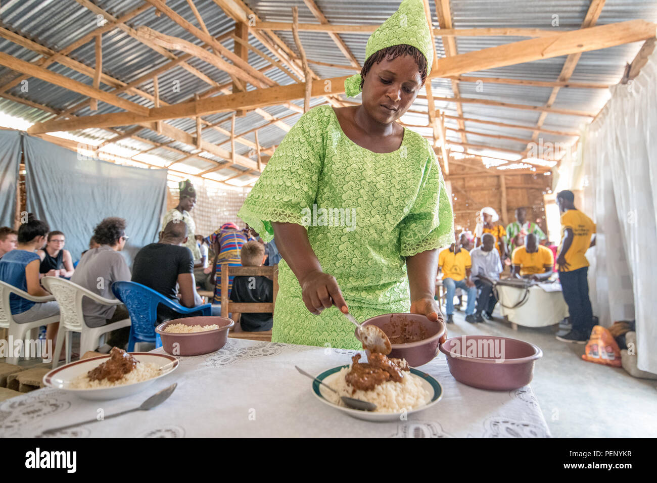 Una donna in abiti colorati serve cibo su piastre in Ganta, Liberia. Foto Stock
