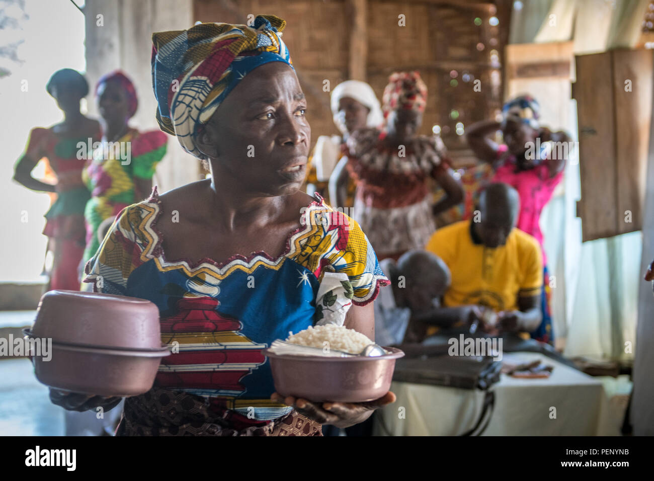 Una donna che tiene le ciotole di cibo per un pasto alla chiesa in Ganta, Liberia Foto Stock