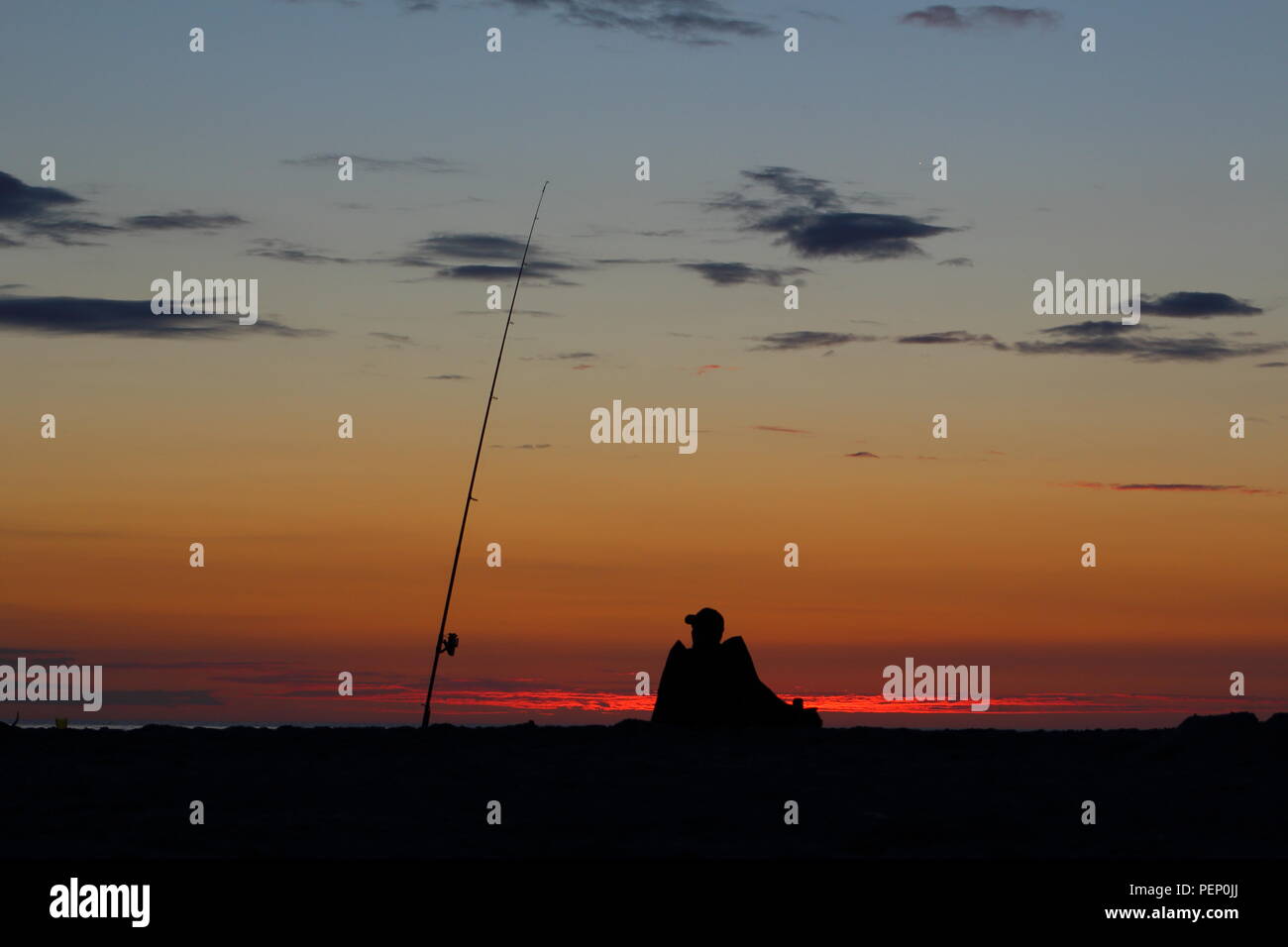 Navigare il pescatore con la canna da pesca sul mar baltico spiaggia al tramonto Foto Stock