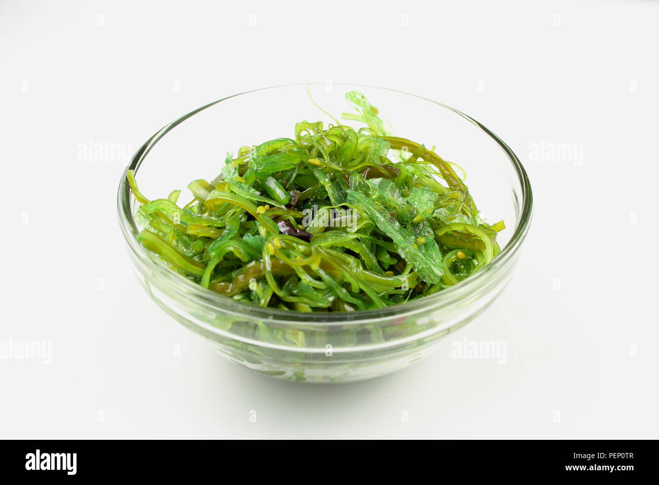 Insalata di wakame con sesamo in una piccola ciotola di vetro isolato su uno sfondo bianco Foto Stock
