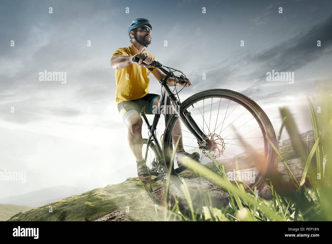 Il giovane montare gli uomini nel casco di conquistare le montagne su una bicicletta. La moto, natura, bicicletta, sport, ciclo, extreme, lifestyle, avventura e sport concept Foto Stock