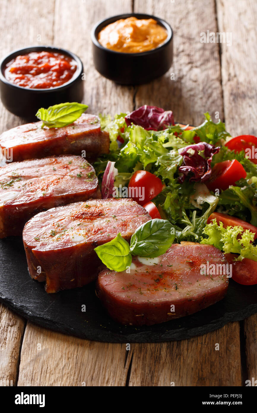 Speziato arrosto di maiale petto e fresca insalata di verdure sono serviti di ketchup e senape sul piano verticale. Foto Stock