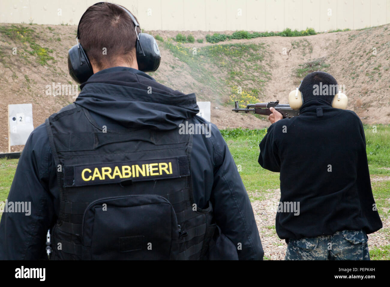 Un Carabinieri orologi trainer un poliziotto iracheno come lui spara un AK-47 fucile da assalto a un bersaglio durante la precisione di tiro avanzato della formazione di Camp Dublin, Iraq, 23 gennaio, 2016. I carabinieri sono la formazione poliziotti iracheni come parte della Combined Joint Task Force - Funzionamento inerenti risolvere la costruzione di capacità del partner di missione. Ai poliziotti che eseguire bene durante il corso di formazione di base vengono selezionati per la formazione avanzata come questo. Il corso di formazione prepara i poliziotti per proteggere e stabilizzare città irachene dopo altre Forze di Sicurezza Irachene retake loro da uno Stato islamico dell Iraq e il levante. ( Foto Stock
